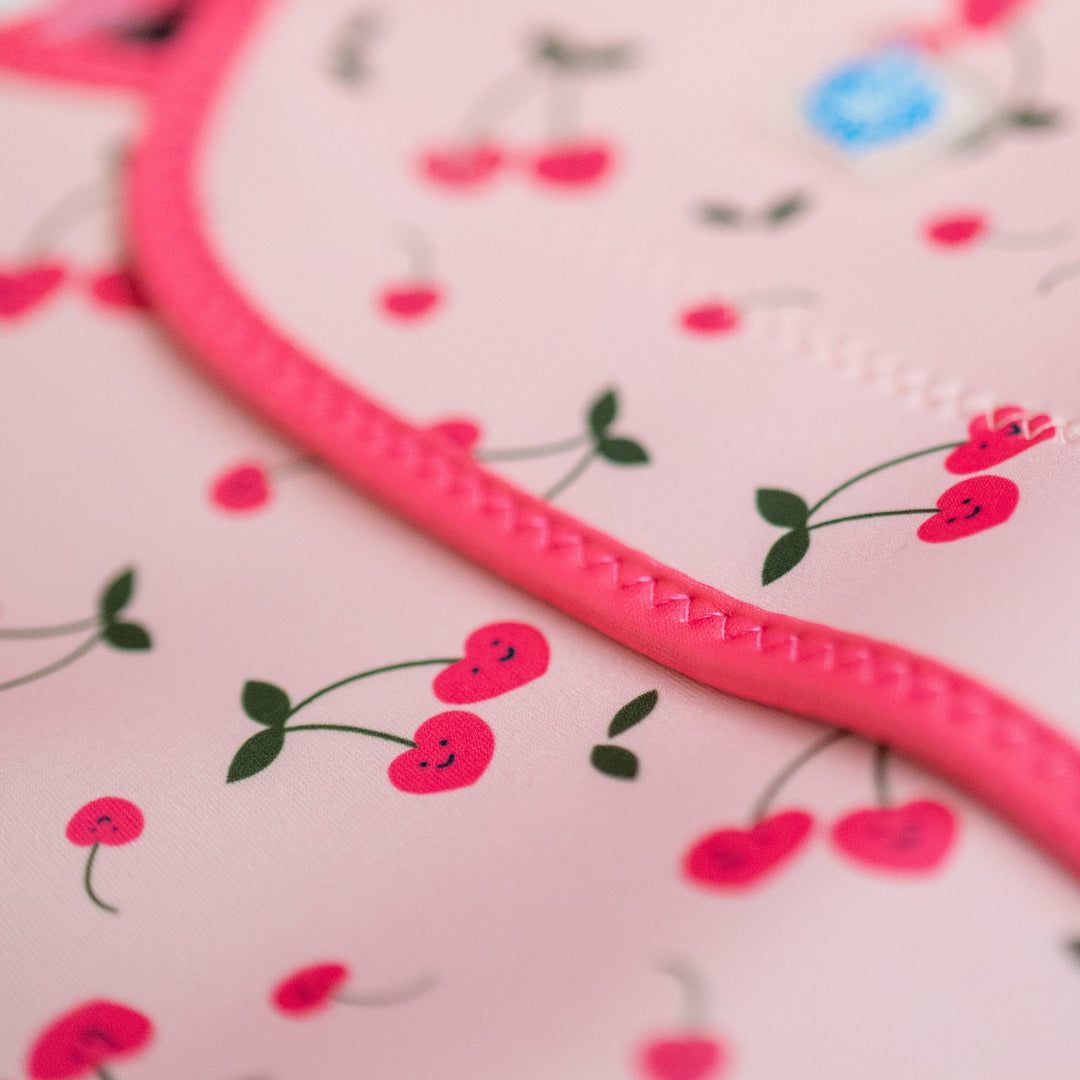 Close up of neoprene baby wrap wetsuit in pink and cherries themed print.