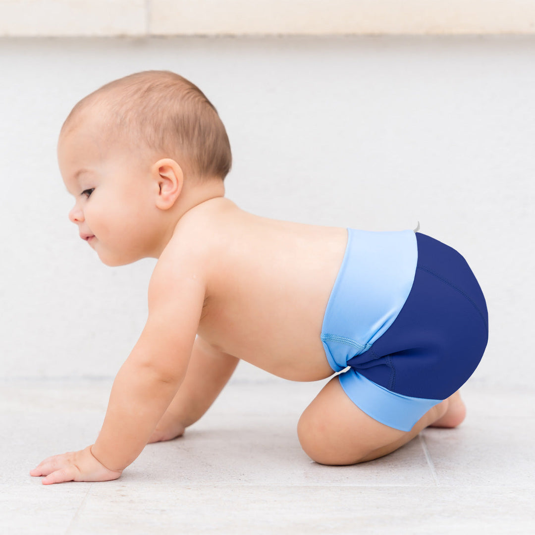 Little one wearing neoprene swim diaper in navy with blue ribs.