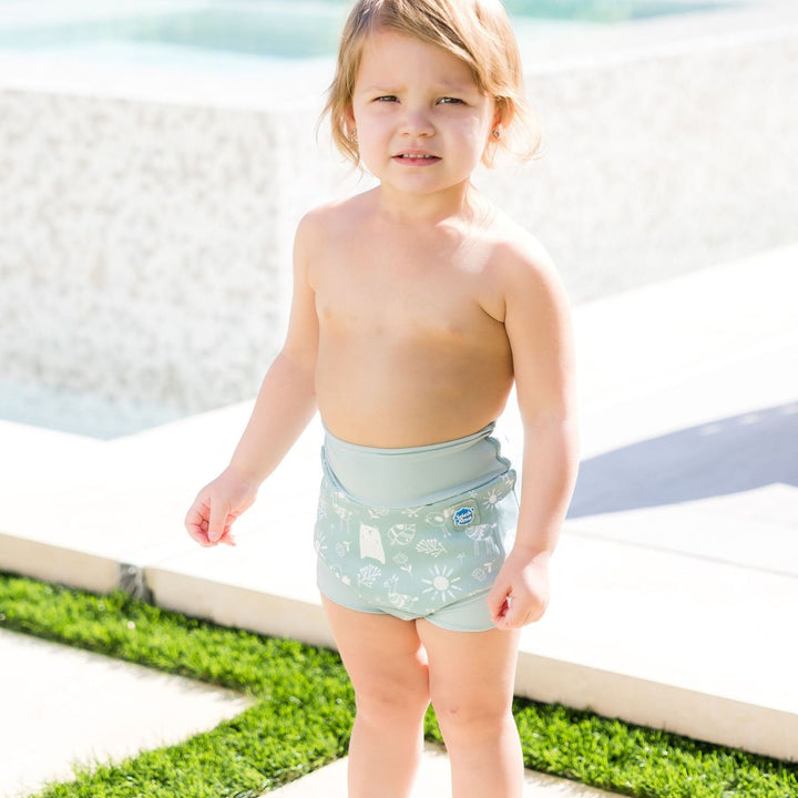 Little one wearing Happy Nappy in greenish blue, featuring animals themed print in white. Front.