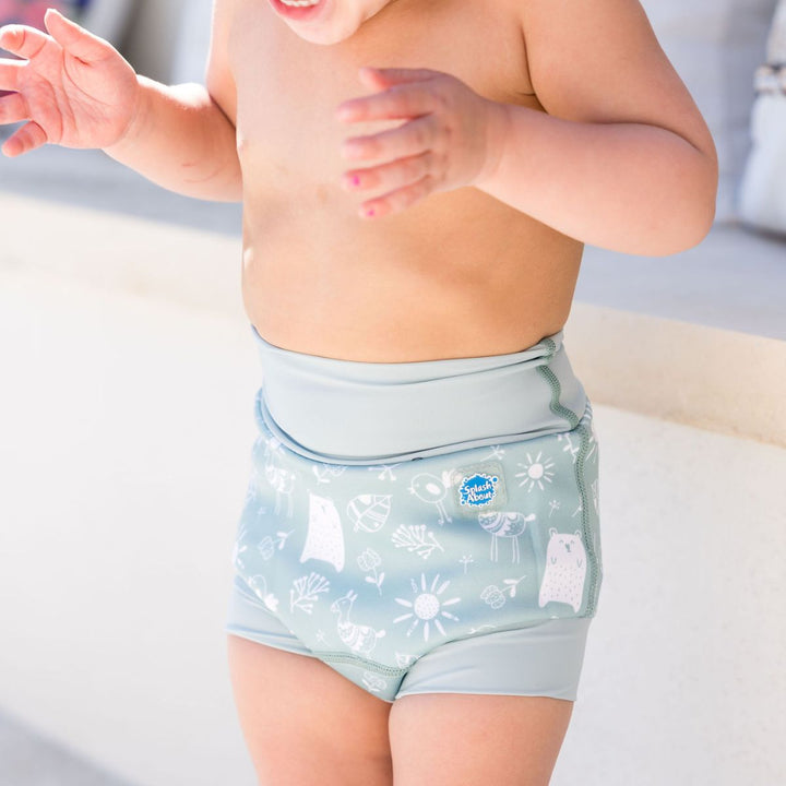 Little one wearing Happy Nappy in greenish blue, featuring animals themed print in white. Front, close up.