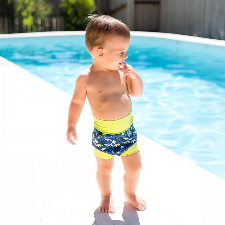 Little one wearing neoprene swim diaper in navy, with lime ribs and turtles themed print.