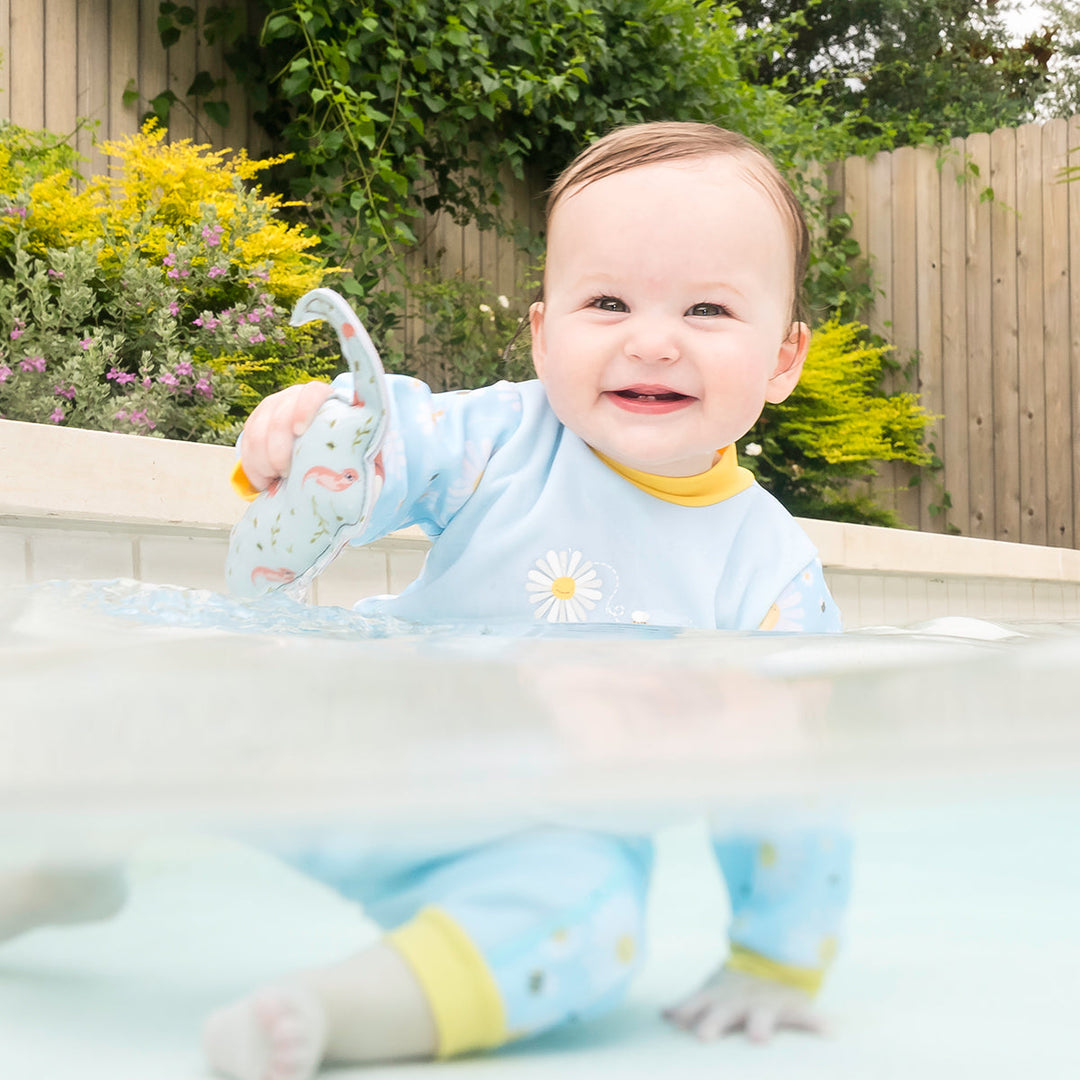 Little one wearing fleece-lined baby wetsuit in baby blue with yellow trims and daisies themed print.