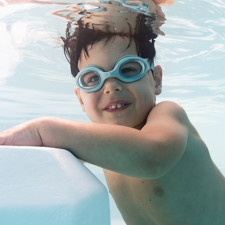 Little one wearing green goggles underwater