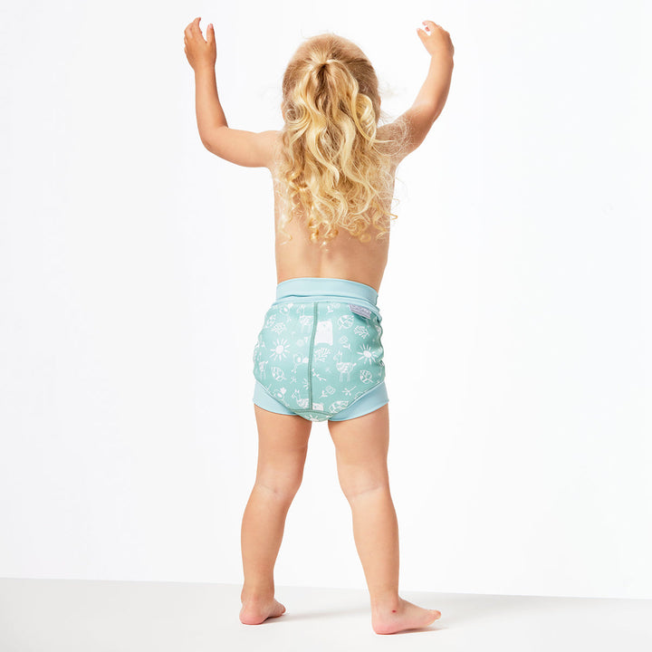 Little one wearing Happy Nappy in greenish blue, featuring animals themed print in white. Back.