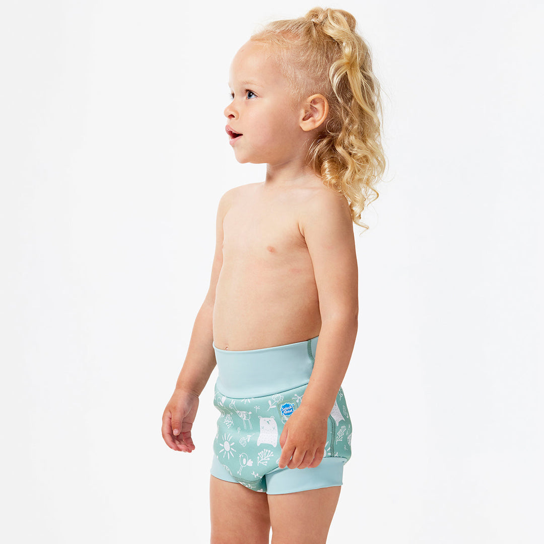 Little one wearing Happy Nappy in greenish blue, featuring animals themed print in white. Side.